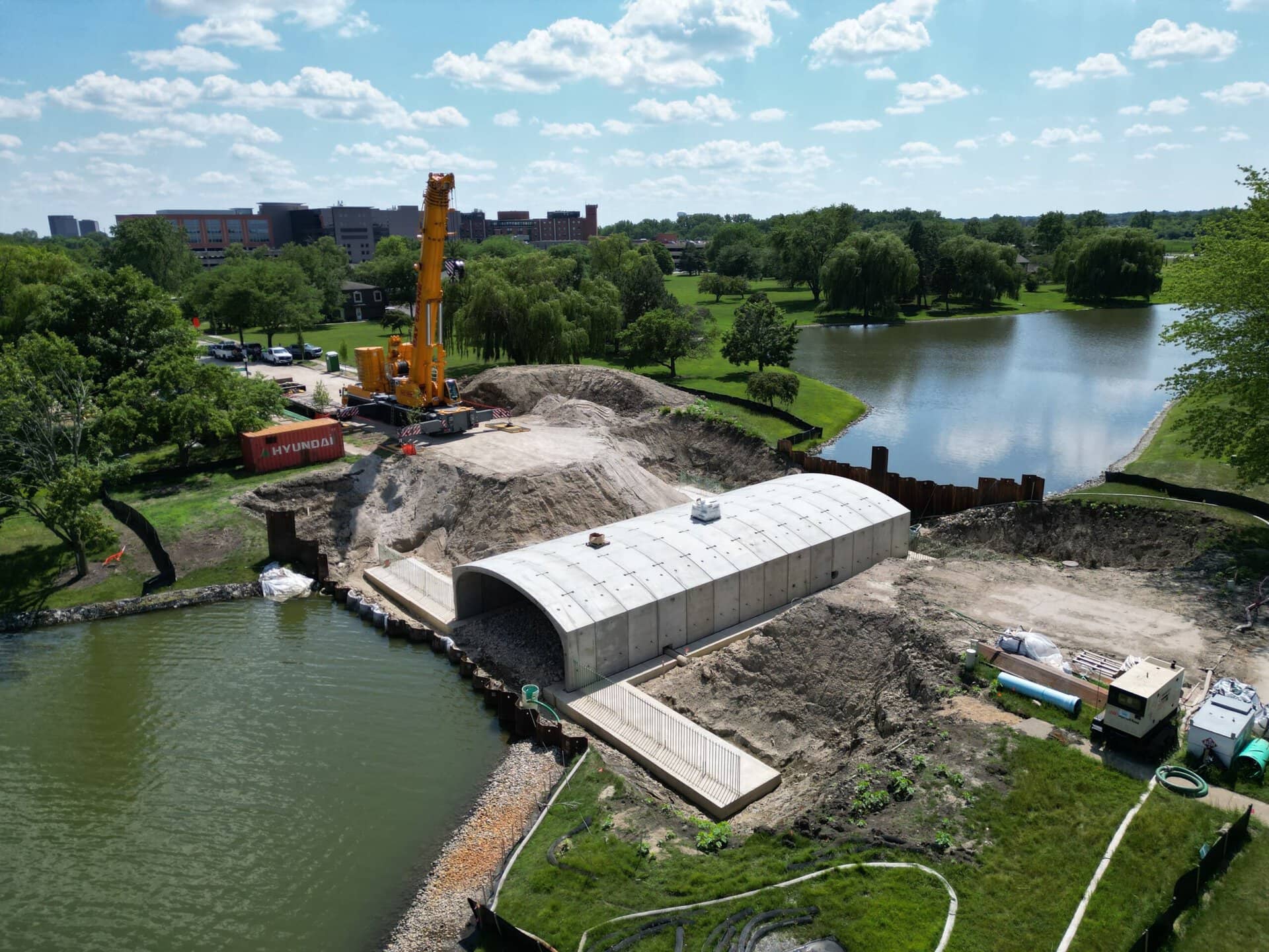 Water treatment plant construction site with crane and storage tank near a lake.