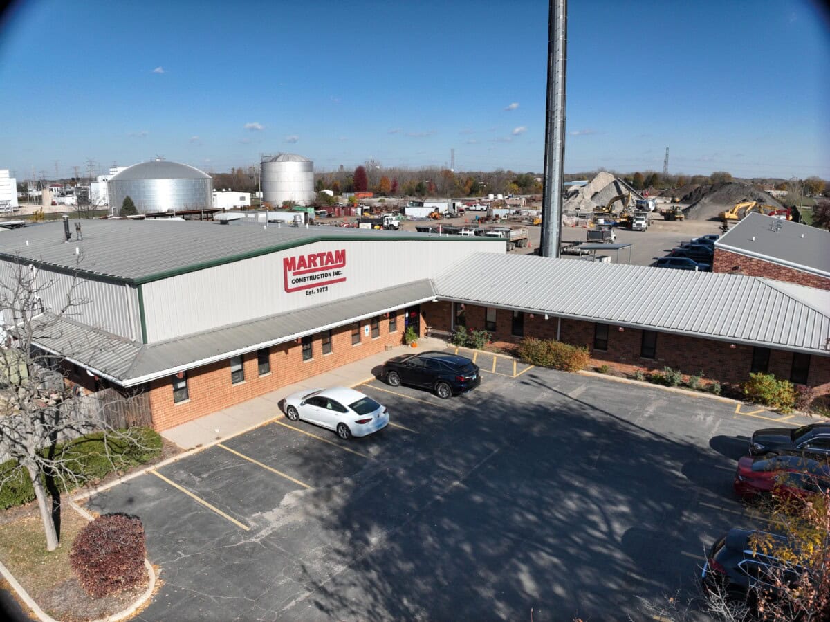 Construction company building with parking lot and industrial background.