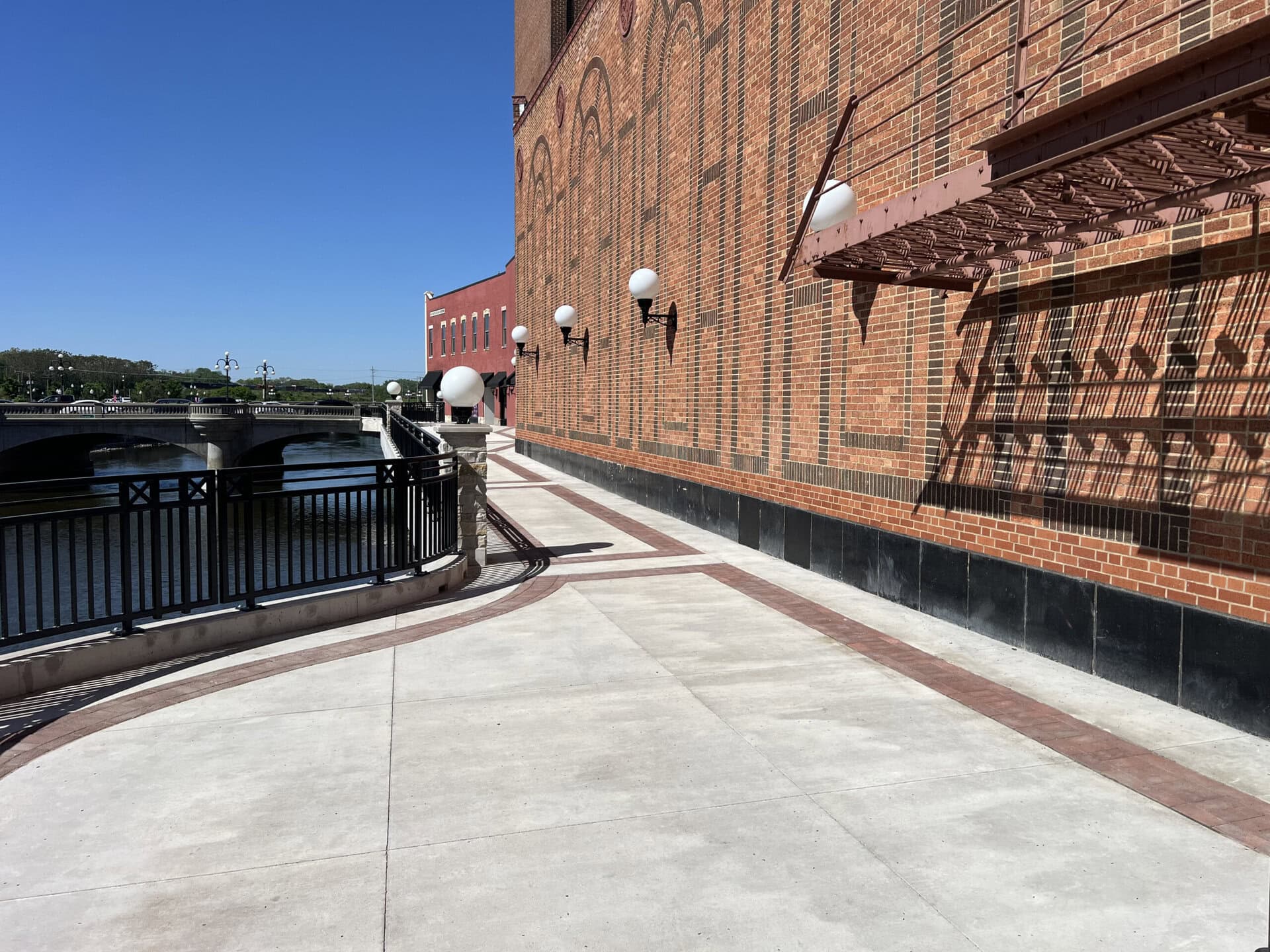 Exterior of a brick building with a paved walkway along the riverbank, showcasing construction and u.