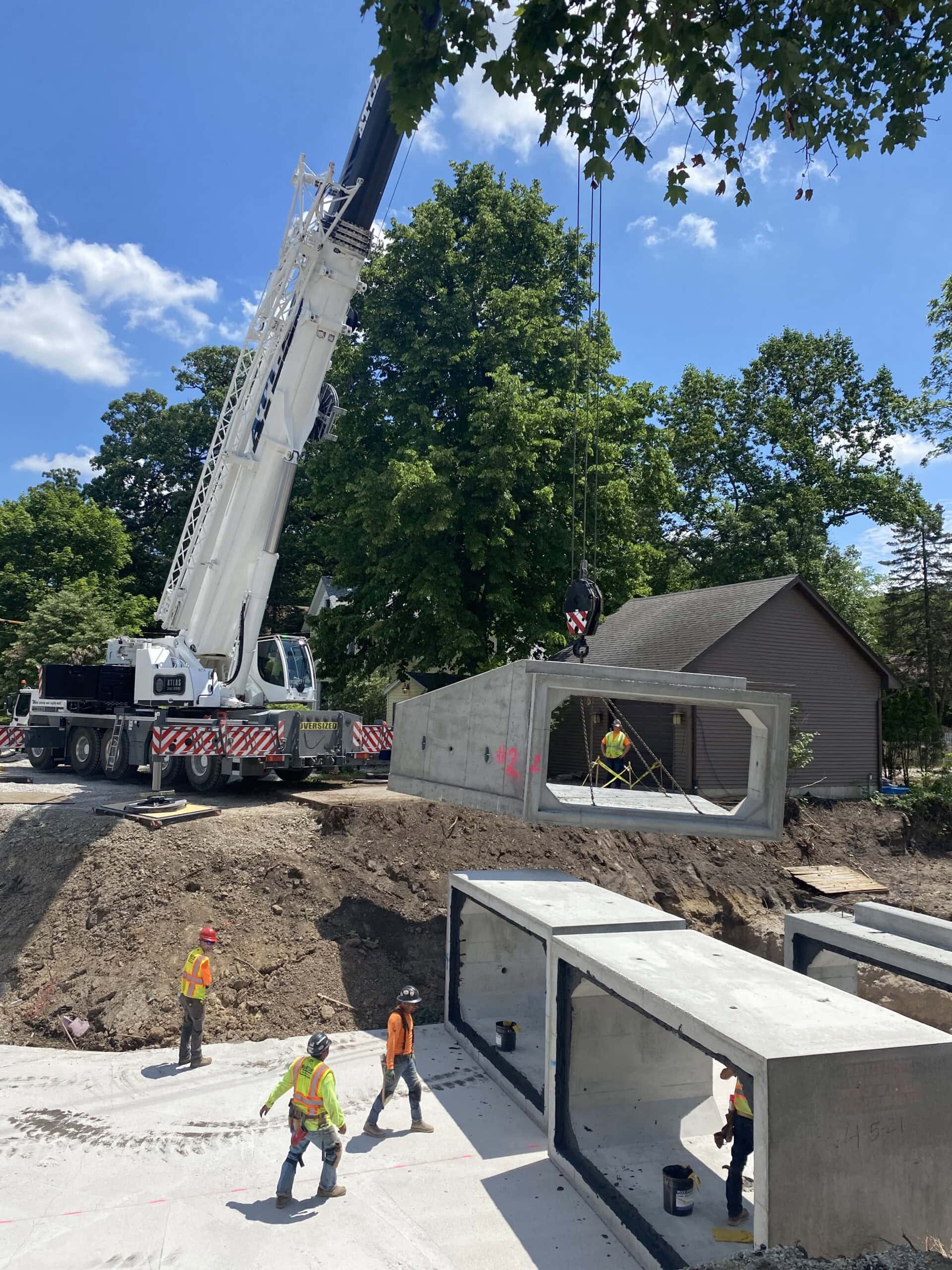 Crane lifting large concrete modules during residential construction project.